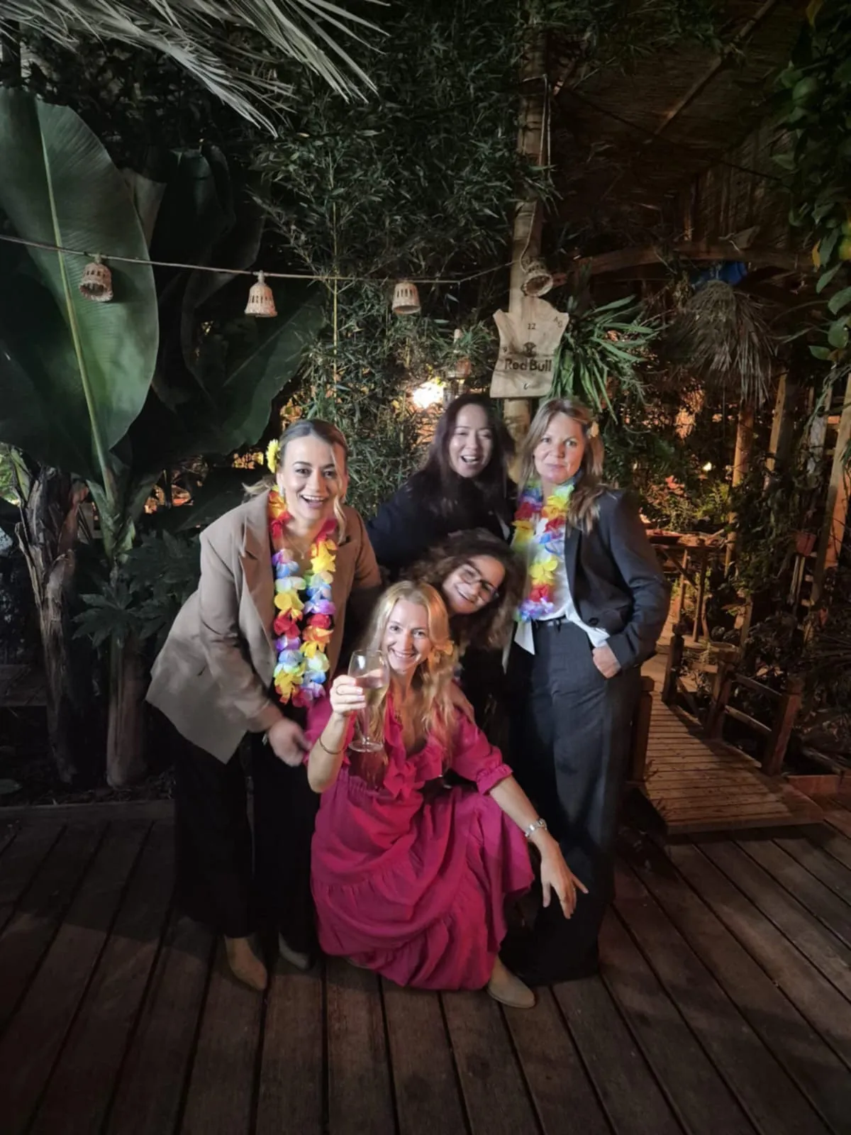 Four friends at a night party at the venue, wearing colorful floral leis
