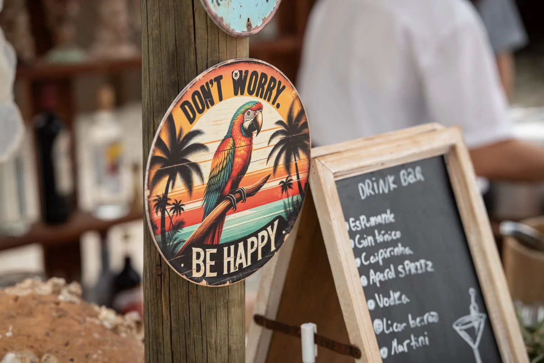 Decorative sign 'Don't worry be happy' with a colorful macaw and a chalkboard listing the bar menu