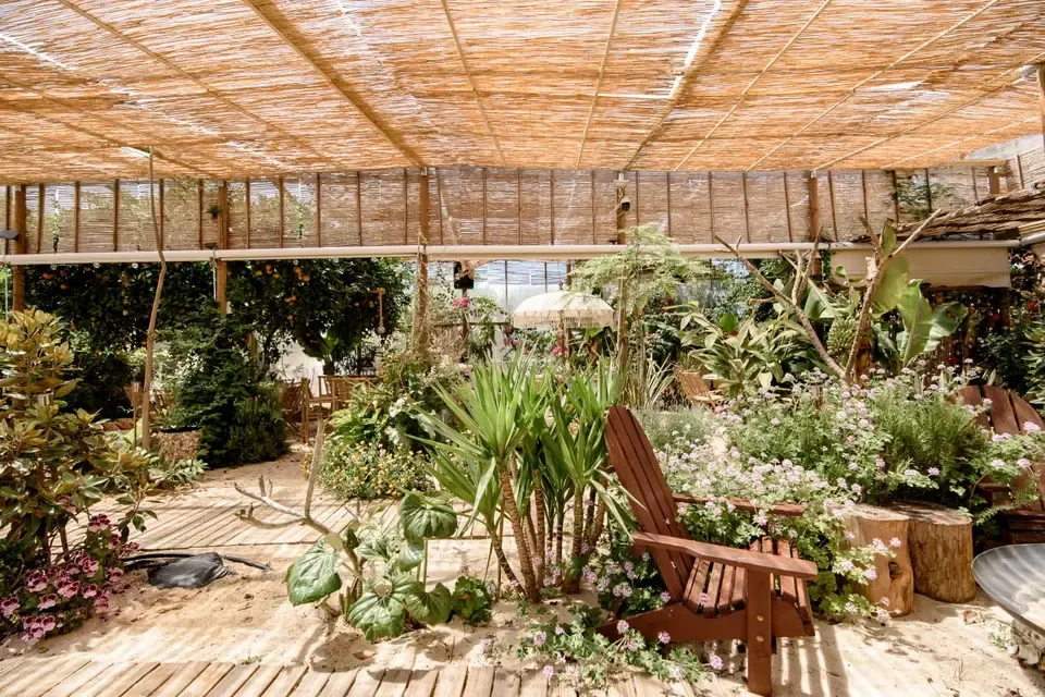 Wide view of the venue's covered tent interior, with foliage and wooden chairs