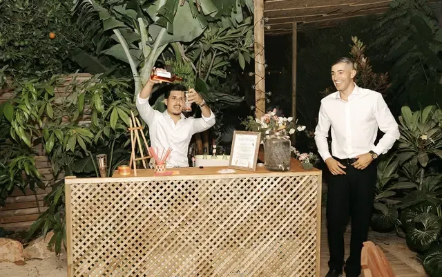 Venue bar at night, with staff preparing cocktails amid tropical foliage