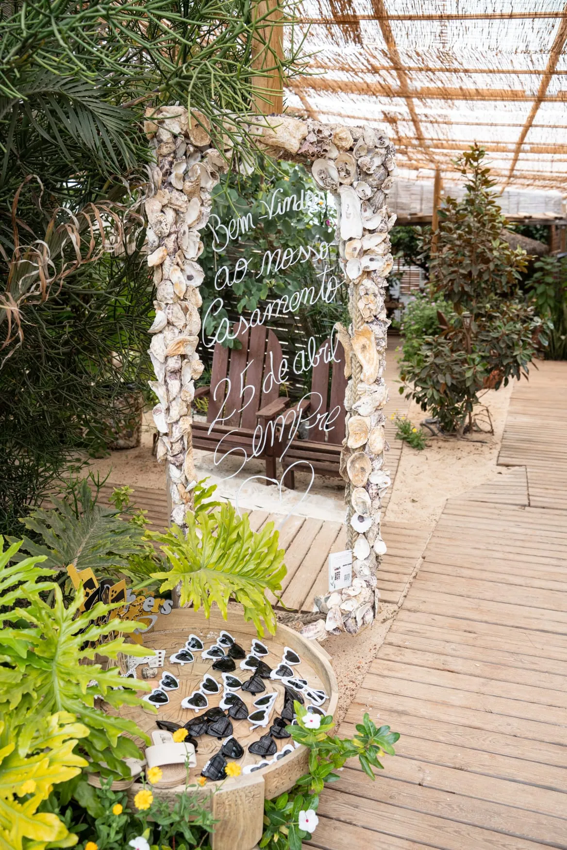 Wedding welcome sign decorated with seashells and a natural frame, in the venue's garden